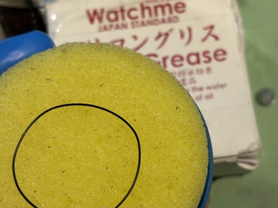 黄色いシリコングリース用スポンジの上に載せられた黒いゴムパッキン