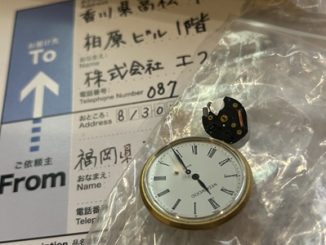 宅配便の伝票の上に置かれたウェッジウッドの時計本体と外れたムーブメントパーツ