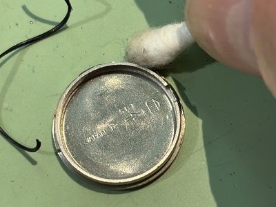 綿棒で裏蓋の溝を丁寧に掃除する様子