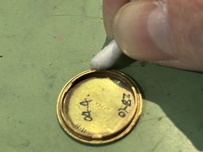 綿棒を使って裏蓋の内側のフチや溝を綺麗に清掃している様子