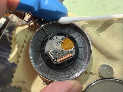 古くなった電池を取り外し、ケース内側を綿棒で観察・清掃する様子
