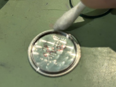 外した裏蓋の溝やフチの汚れを綿棒でお掃除している様子