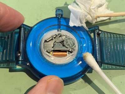 裏蓋を開けた内部フチの汚れを綿棒で清掃する様子