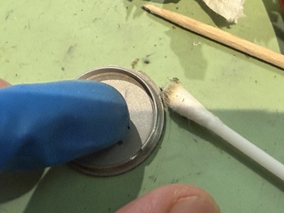 裏蓋の溝に溜まった汚れを綿棒で掃除する様子
