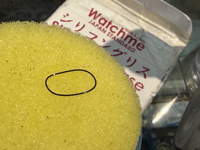 シリコングリース塗布器(イエローのスポンジ)に乗せられた新品の黒いOリングパッキン
