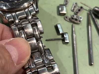 修理中の時計ブレスレットに分解したコマパーツを仮組みして適合を確認する様子