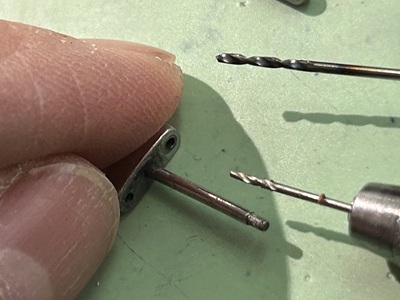 精密ドリルを使って極小パーツのピン穴を慎重に拡大・再加工している手元
