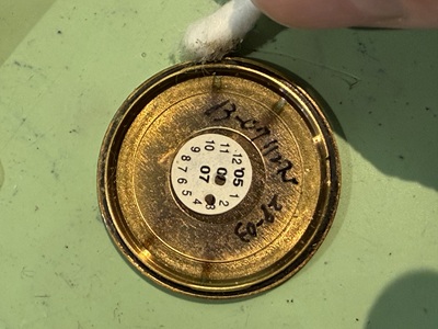 外した裏蓋の内側と溝を綿棒で清掃している手元