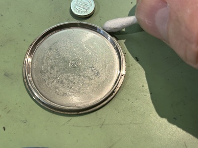 パッキンを取り外した裏蓋側の溝を綿棒で清掃している手元
