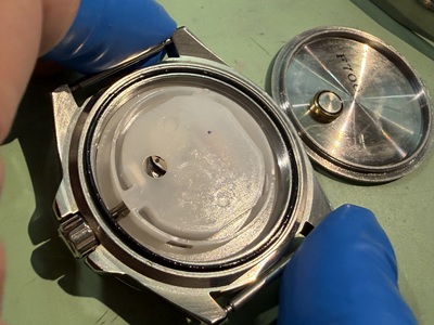 ムーブメントの上に白いプラスチック内蓋を戻し密閉感を保つ作業
