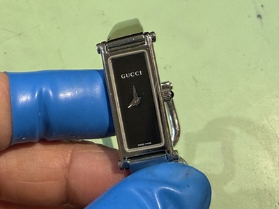 手に持たれた黒文字盤のGUCCI（グッチ）バングルタイプの腕時計