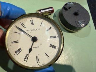 時計枠に新しいムーブメントを組み込んで調整している手元画像