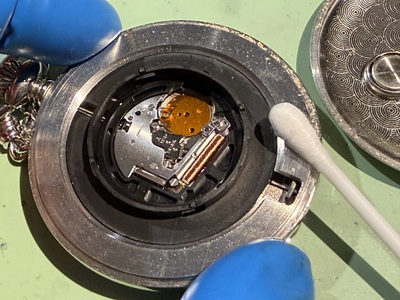 綿棒を使ってムーブメントのフチやケースの溝を掃除している様子