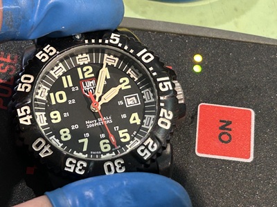 パルスチェッカーの上に置かれたルミノックスと、緑色に点灯するランプ