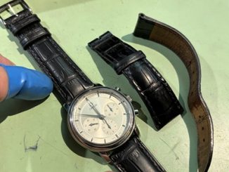 時計本体に新しい革ベルトを取り付け、外した旧ベルトと並べて固定状態を確認している様子